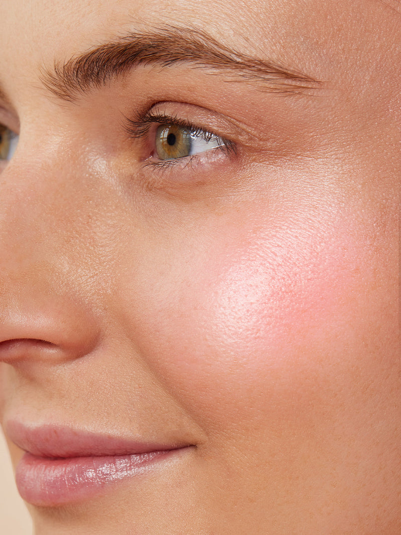 Pink opal -- liquid highlighter on white background with cap next to bottle