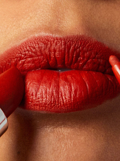 Dirty Love -- close up of model lips applying red lipstick and lip liner to top and bottom lip