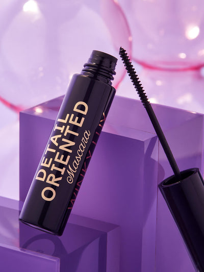 Type A Black -- detail oriented mascara component opened and leaning on glass surface on purple background