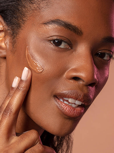 Deep/Plus -- close up of brunette model smiling with tinted moisturizer spf 30 on her cheek bone