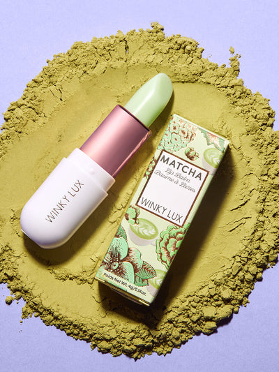 clear -- matcha lip balm and box laying down in matcha on purple backgrround