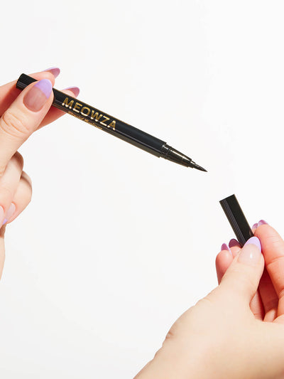 Black -- close up of model's hands holding meowza liquid eyeliner on white background