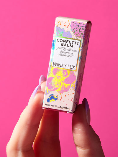 rainbow confetti -- hand holding up glitter confetti ph balm in box on pink background