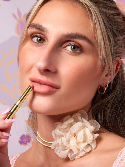 stripped down -- close up of blonde model applying skinny plump demi matte plumping lipstick