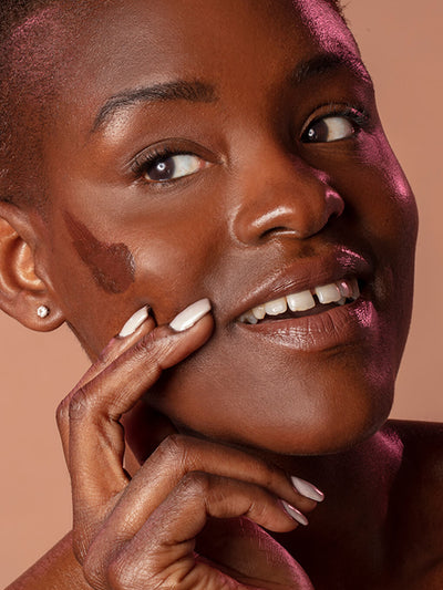 Rich -- close up of brunette model smiling with tinted moisturizer spf 30 on her cheek bone