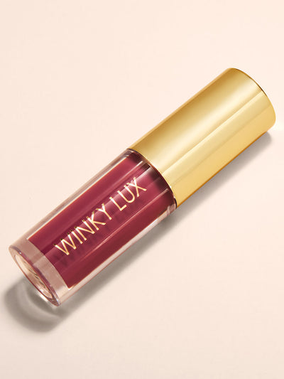Berry -- flat lay of berry pink tinted lip oil with cap on