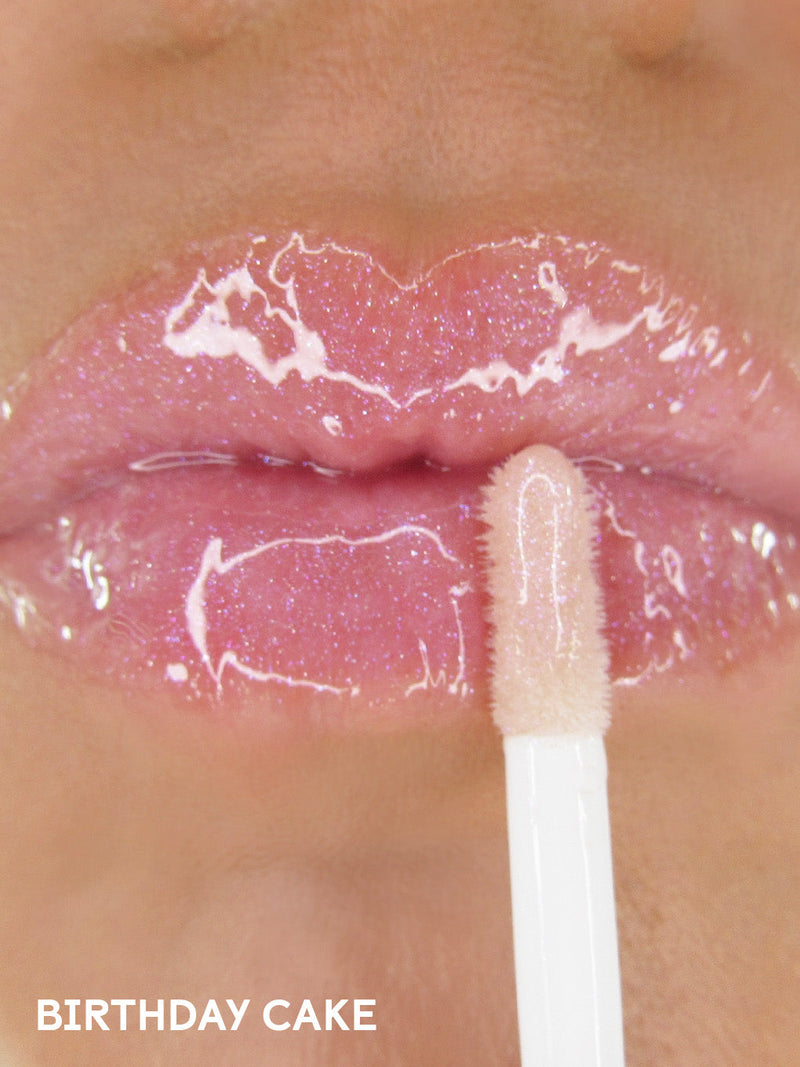 birthday cake shimmer -- shimmer pink lip oil with cap off on white background