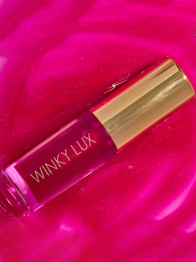 crave -- deep pink lip oil component lying on top of glossy lip oil goop