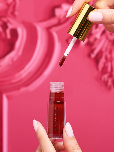 Enchanted -- stylized shot of model pulling tinted lip oil application out of component