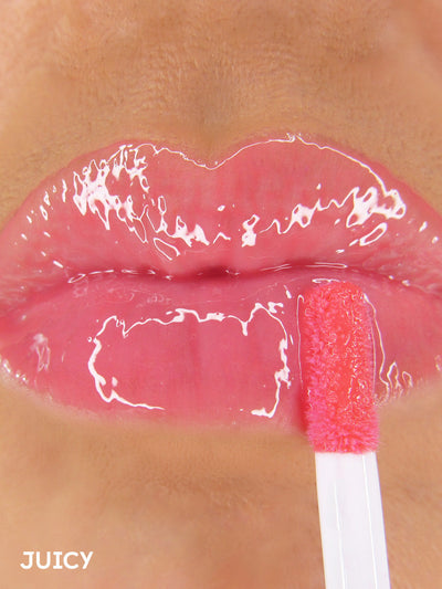 Juicy -- close up of model applying pink tinted lip oil to lips