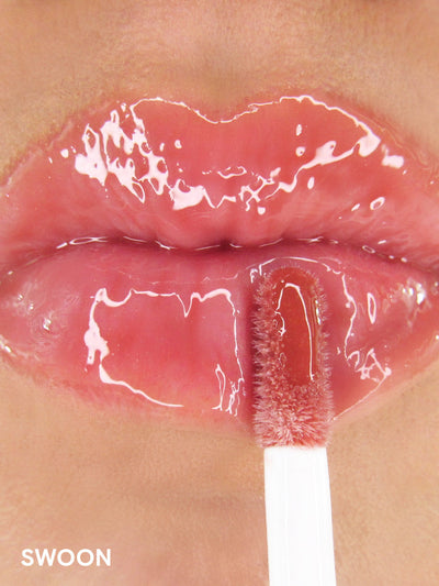 Swoon -- close up of model applying pink tinted lip oil on lips
