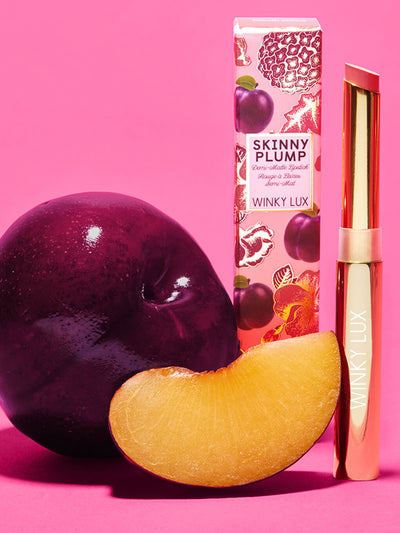 corner office -- skinny plump demi matte plumping lipstick standing next to box and plum