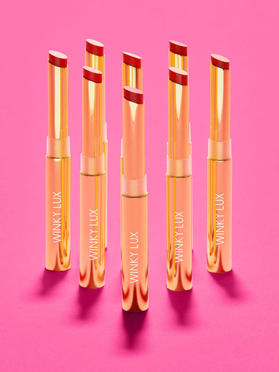 corner office -- 8 shades of skinny plump demi matte plumping lipstick standing on hot pink surface