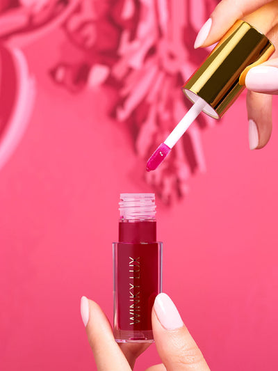 crave -- stylized image of model hand pulling applicator out of deep pink lip oil component with pink background